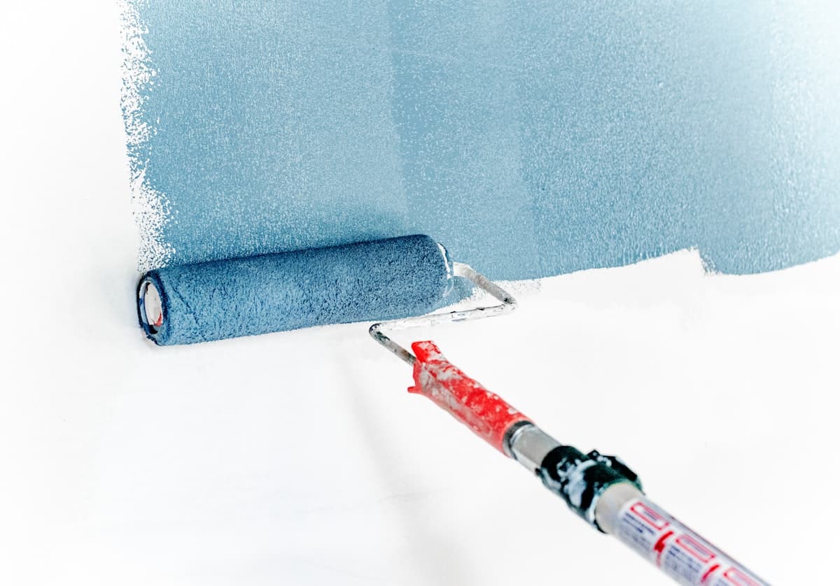 A professional Dublin painter applying weather-shield masonry paint to a window frame